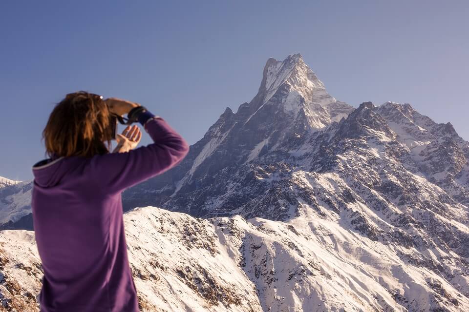 Mardi Himal trekking – vrouwelijke wandelaar geniet van uitzicht op de besneeuwde Machapuchare